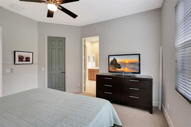 bedroom featuring baseboards, light colored carpet, ensuite bath, and ceiling fan