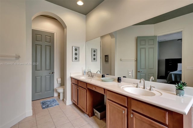 bathroom featuring tile patterned flooring, toilet, double vanity, ensuite bathroom, and baseboards