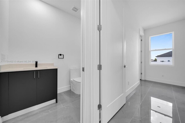 1212 NW 35th Pl, Cape Coral, FL 33993 - bathroom featuring toilet, baseboards, marble finish floors, and vanity