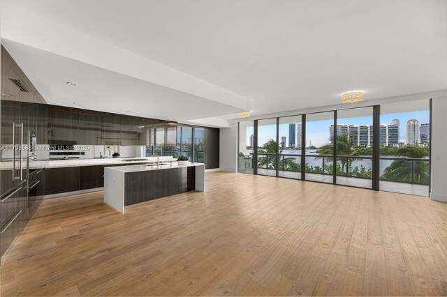kitchen featuring modern cabinets, open floor plan, a wall of windows, light countertops, and light wood-type flooring