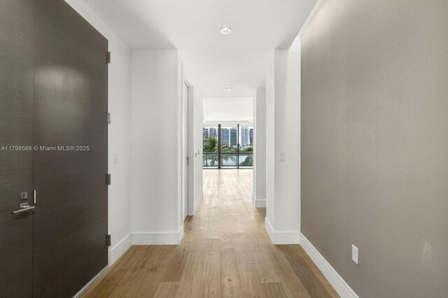 hallway featuring light wood-style flooring and baseboards