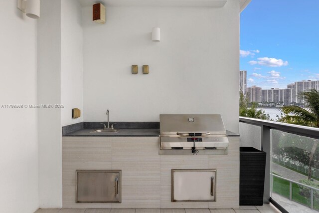balcony featuring grilling area, a sink, an outdoor kitchen, and a view of city