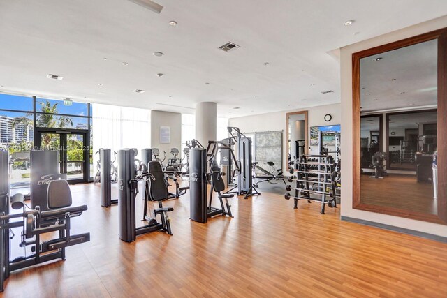 gym featuring light wood finished floors, a wall of windows, and recessed lighting