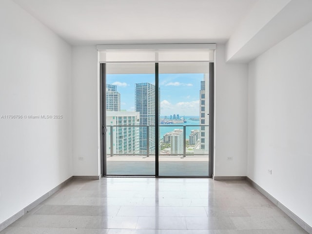 spare room with expansive windows, baseboards, and a view of city