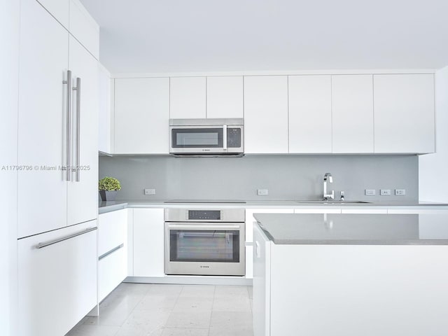 kitchen featuring appliances with stainless steel finishes, a sink, and white cabinetry