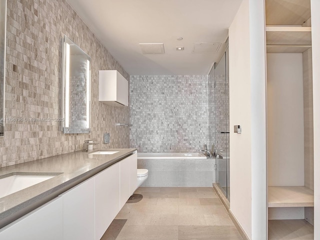 full bath with tile walls, a bath, a stall shower, double vanity, and toilet