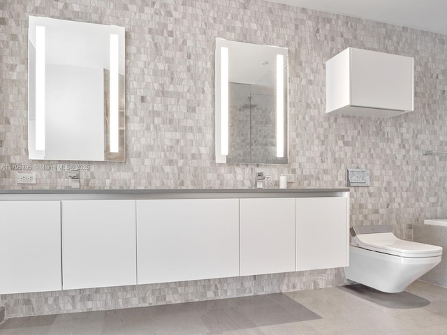 bathroom with tile walls, toilet, and double vanity