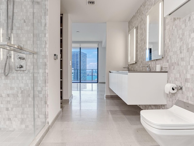 full bath with tile walls, a stall shower, expansive windows, toilet, and double vanity