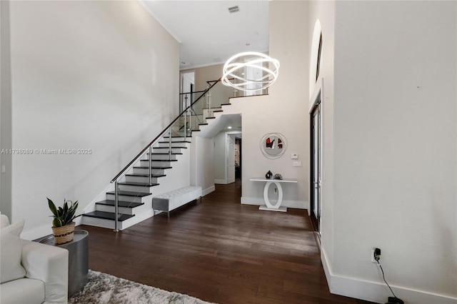 foyer entrance with stairway, a chandelier, a towering ceiling, baseboards, and wood finished floors