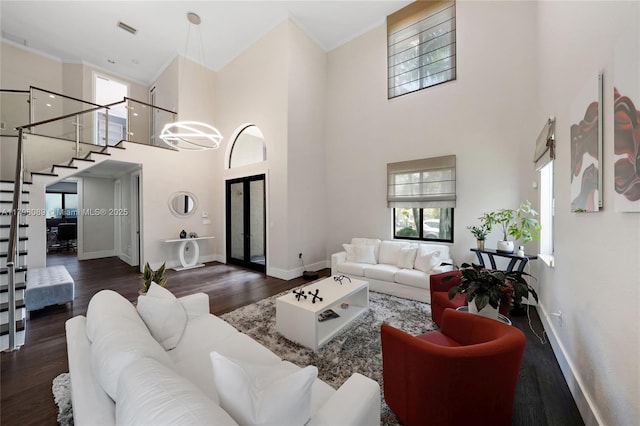 living room featuring a high ceiling, wood finished floors, baseboards, stairs, and ornamental molding