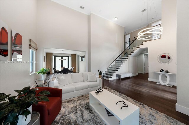 living area with wood finished floors, a towering ceiling, stairs, baseboards, and a chandelier