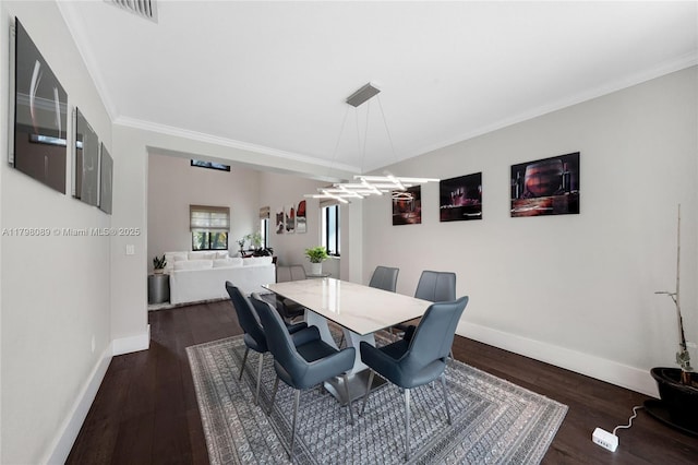 dining area featuring wood finished floors, crown molding, and baseboards