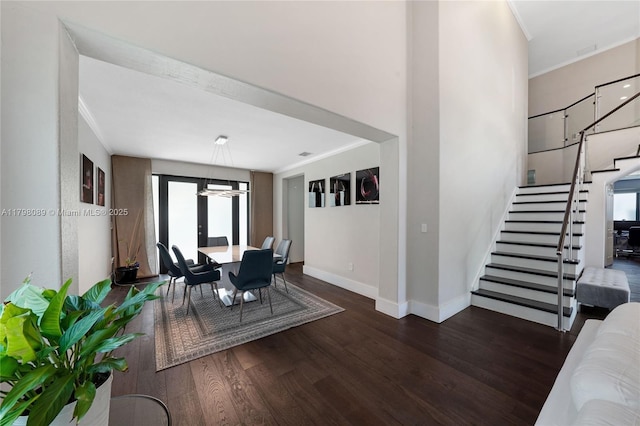dining space with crown molding, stairs, wood finished floors, baseboards, and a chandelier