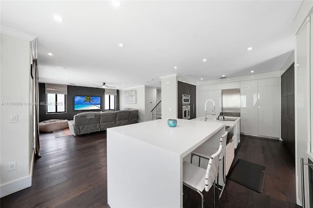 kitchen featuring stainless steel oven, white cabinets, a kitchen bar, modern cabinets, and recessed lighting