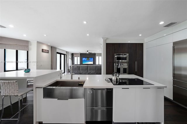 kitchen with modern cabinets, appliances with stainless steel finishes, light countertops, a sink, and open floor plan