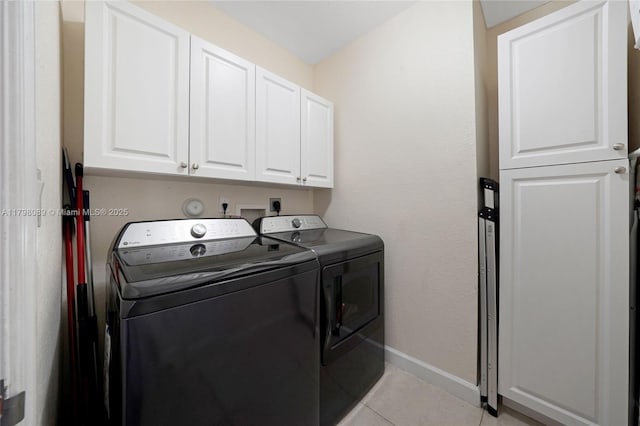clothes washing area with washer and dryer, cabinet space, baseboards, and light tile patterned floors