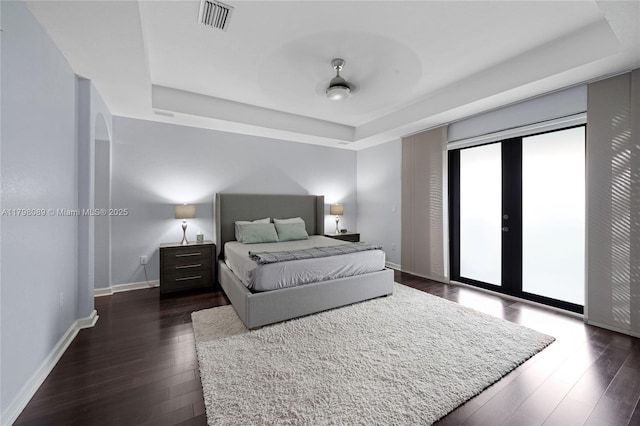 bedroom featuring a raised ceiling, access to outside, dark wood-type flooring, baseboards, and french doors