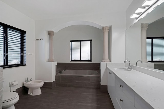 bathroom with decorative columns, a garden tub, a bidet, toilet, and vanity