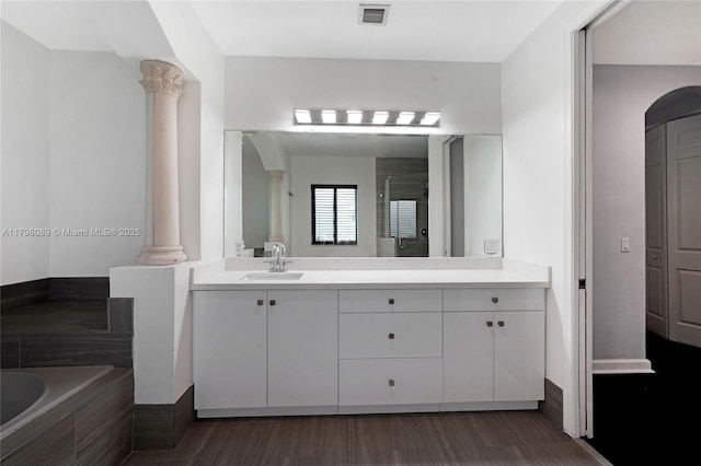 full bathroom with decorative columns, a stall shower, a garden tub, vanity, and wood finished floors