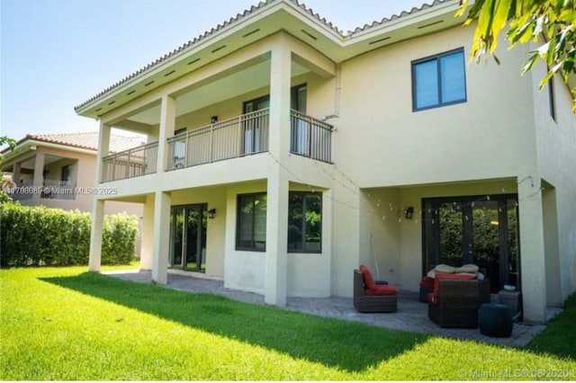 rear view of house featuring stucco siding and a yard