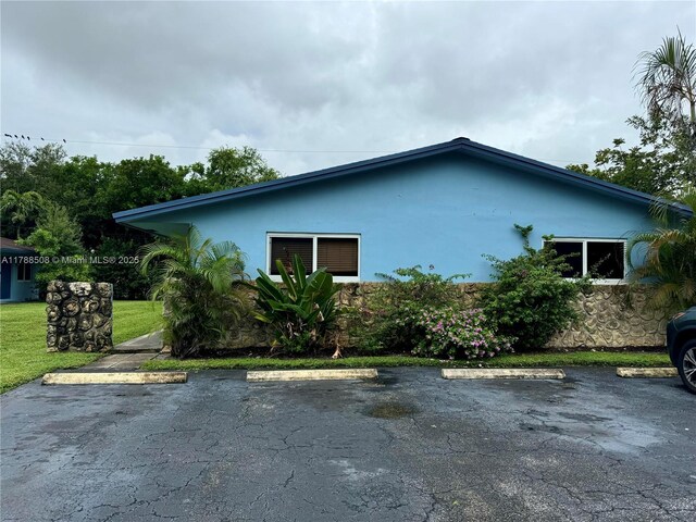 2631 SW 13th Ave, Fort Lauderdale, FL 33315 - view of side of property featuring uncovered parking, stucco siding, and a lawn