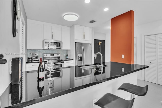 2650 SW 37th Ave Unit 906, Miami, FL 33133 - kitchen featuring stainless steel appliances, a sink, a kitchen bar, white cabinetry, and tasteful backsplash