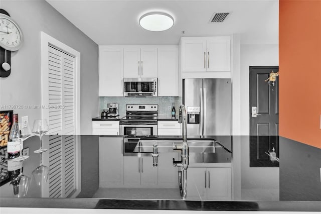 2650 SW 37th Ave Unit 906, Miami, FL 33133 - kitchen featuring appliances with stainless steel finishes, a sink, dark countertops, tasteful backsplash, and white cabinetry