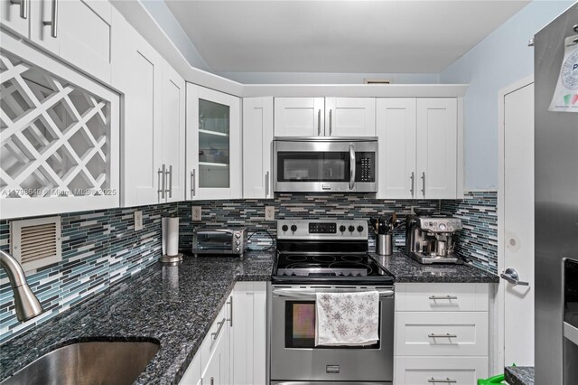 1000 W Ave Unit 308, Miami Beach, FL 33139 - kitchen featuring appliances with stainless steel finishes, a sink, white cabinetry, backsplash, and glass insert cabinets