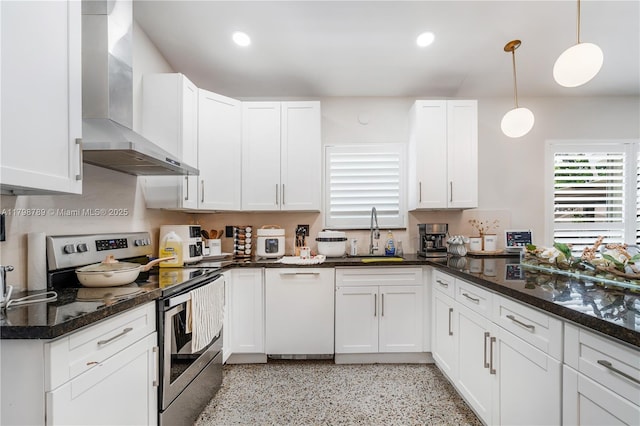 kitchen with stainless steel range with electric stovetop, wall chimney exhaust hood, a sink, white cabinets, and dark speckled floor