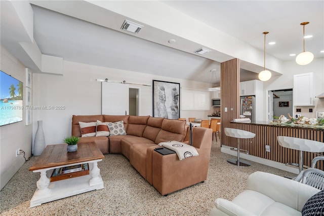 living room featuring dark aggregate flooring, recessed lighting, and decorative columns