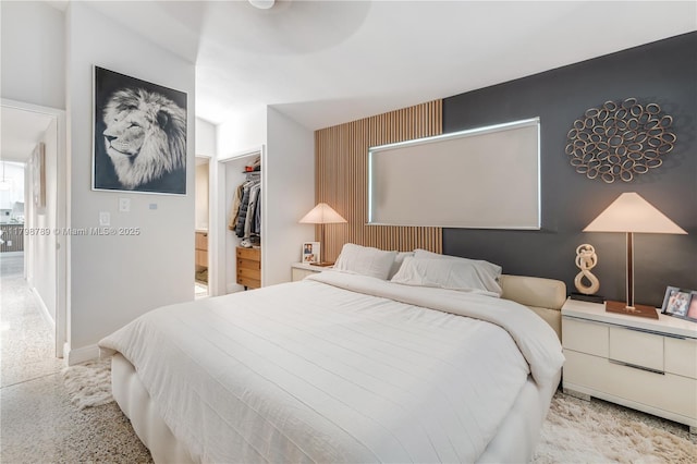bedroom with a spacious closet, baseboards, and a closet