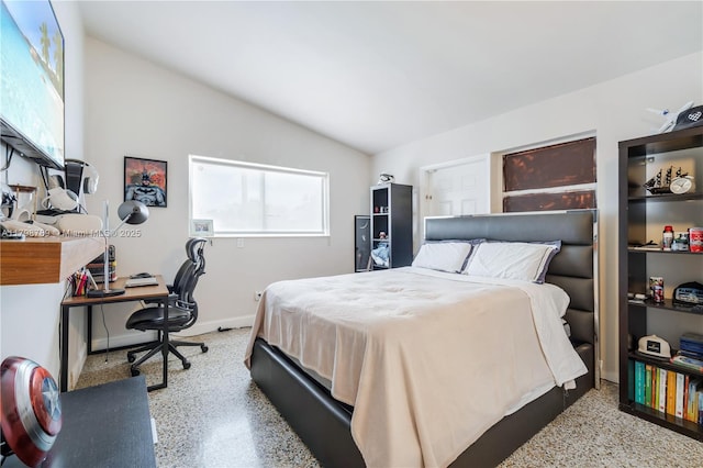 bedroom featuring speckle patterned floor, lofted ceiling, an office area, and baseboards