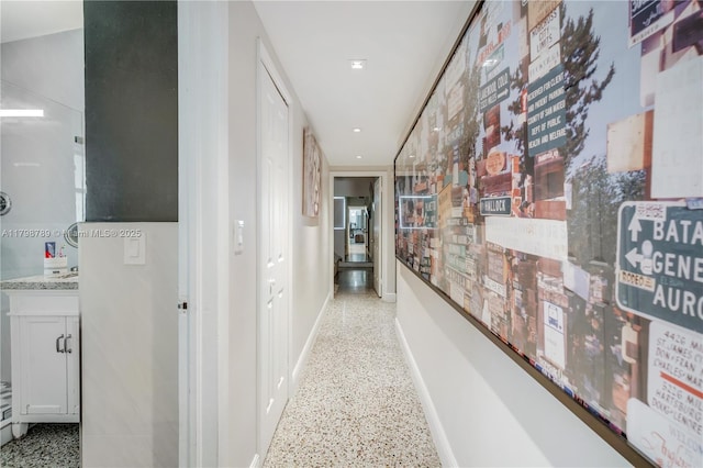 hall featuring dark aggregate flooring and baseboards
