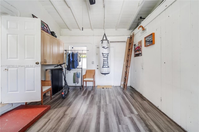 interior space featuring wood finished floors, beam ceiling, and wood walls