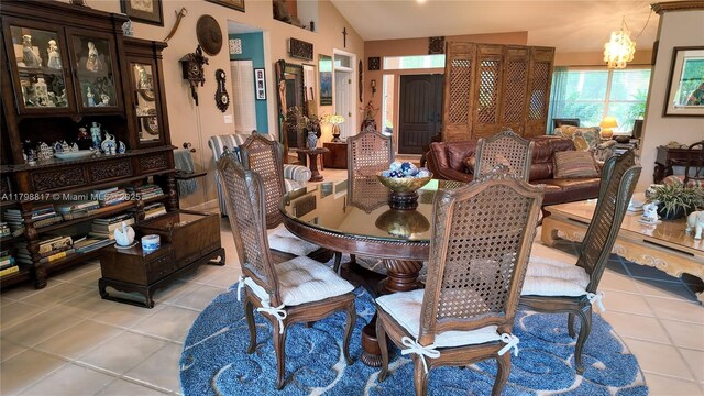 dining area with light tile patterned floors, a chandelier, and vaulted ceiling