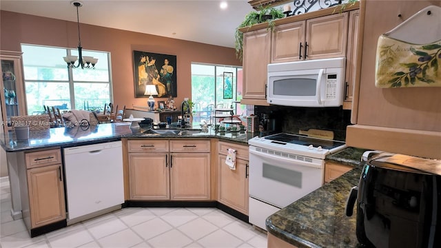 kitchen featuring white appliances, a peninsula, a sink, a chandelier, and decorative light fixtures
