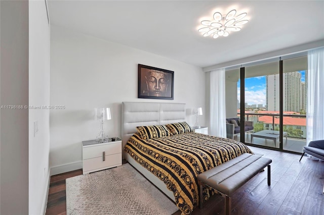 bedroom featuring access to outside, wood finished floors, expansive windows, and baseboards