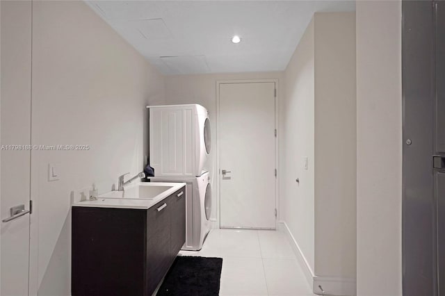 clothes washing area with estacked washer and dryer, light tile patterned flooring, cabinet space, and baseboards