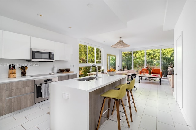 2475 NE 135th St, North Miami, FL 33181 - kitchen with appliances with stainless steel finishes, a sink, modern cabinets, light countertops, and a breakfast bar