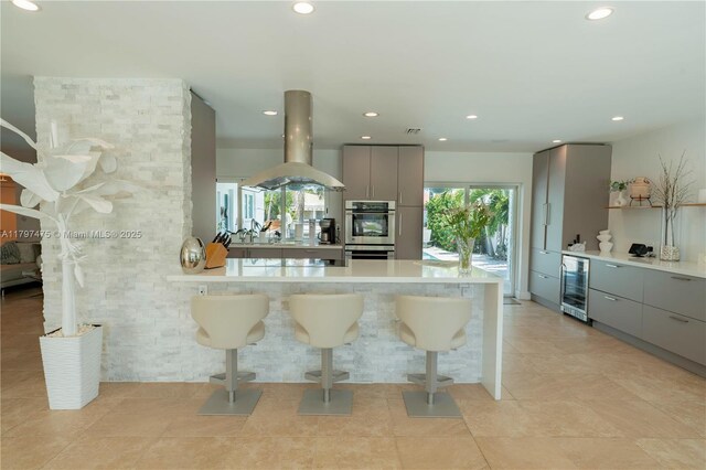 2711 NE 57th Ct, Fort Lauderdale, FL 33308 - kitchen with gray cabinets, island range hood, a kitchen bar, wine cooler, and modern cabinets