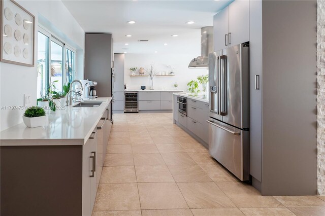 2711 NE 57th Ct, Fort Lauderdale, FL 33308 - kitchen featuring appliances with stainless steel finishes, beverage cooler, wall chimney exhaust hood, gray cabinetry, and a sink