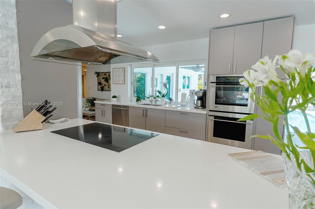 2711 NE 57th Ct, Fort Lauderdale, FL 33308 - kitchen featuring island exhaust hood, stainless steel appliances, light countertops, a peninsula, and recessed lighting