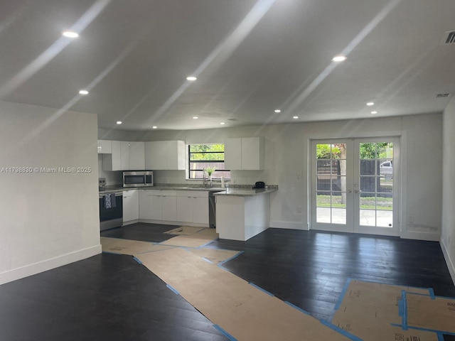 kitchen featuring appliances with stainless steel finishes, french doors, baseboards, white cabinetry, and open floor plan