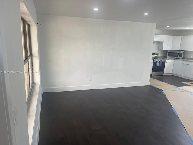 unfurnished living room featuring baseboards, dark wood-type flooring, and recessed lighting