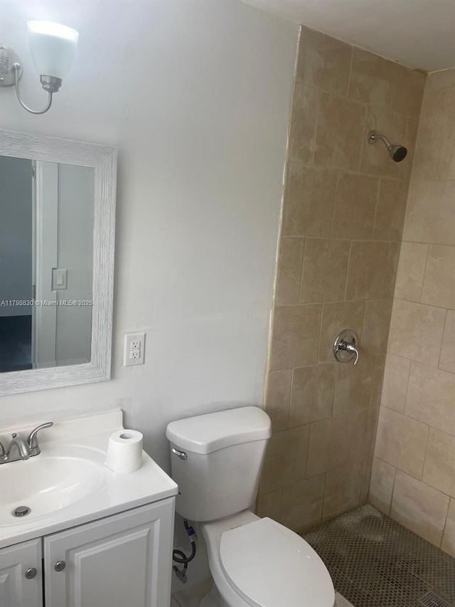 bathroom with tiled shower, toilet, and vanity