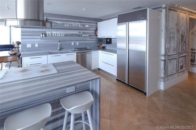 601 NE 36th St Unit 3101, Miami, FL 33137 - kitchen featuring appliances with stainless steel finishes, a sink, modern cabinets, white cabinetry, and wall chimney exhaust hood