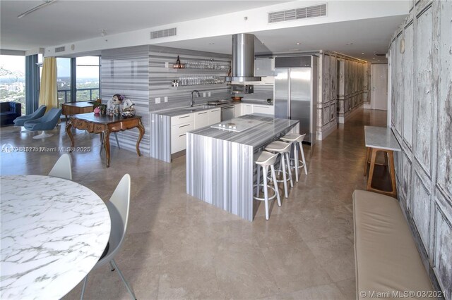 601 NE 36th St Unit 3101, Miami, FL 33137 - kitchen featuring appliances with stainless steel finishes, island exhaust hood, a sink, white cabinets, and light countertops