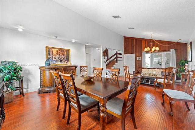 3865 NW 1st Pl, Deerfield Beach, FL 33442 - dining room featuring vaulted ceiling, stairway, a chandelier, wood finished floors, and wood walls