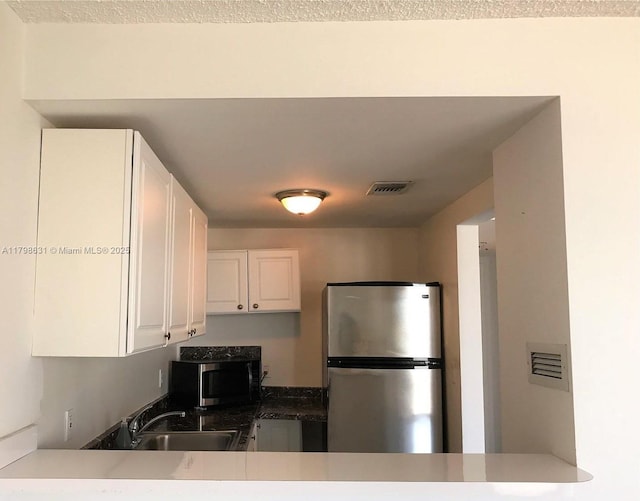 kitchen with stainless steel appliances, a sink, white cabinets, and a peninsula