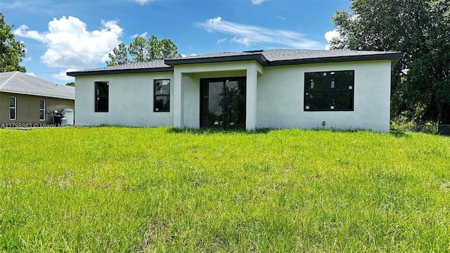 2615 68th St W, Lehigh Acres, FL 33971 - rear view of house with stucco siding and a lawn